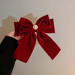 Detailed macro shot of a plush red velvet bow hair clip with a central pearl