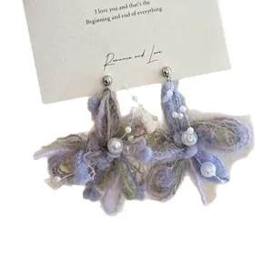 Handcrafted purple yarn flower earrings with white pearls on a romantic white display card
