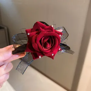 Detailed view of a dark red velvet rose hair clip featuring a black lace mesh bow.