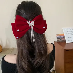 Detailed view of a red velvet bow hair clip with silver butterfly tassel on hair