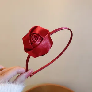 Detail showing the elegant texture of a handmade red satin rose flower headband for girls