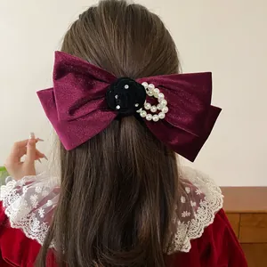 Elegant red velvet bow hair clip with black flower and pearl detail on brown hair