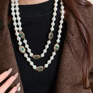 Exquisite vintage double-layered pearl necklace featuring ornate emerald gemstone accents