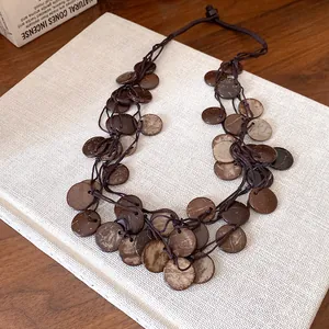 Detail view of irregular round coconut shell disks on a vintage ethnic tassel necklace