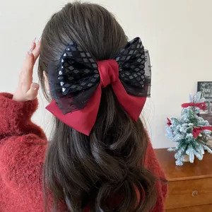 Large red and black sequined bow hair clip worn by a model in a festive Christmas setting