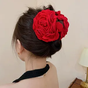 Close-up detailed view of a large red velvet rose hair claw clip on an elegant bun hairstyle.