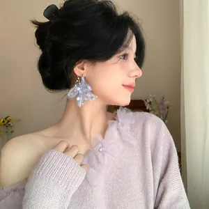 Close-up of lilac knitting flower pearl earrings worn by model for autumn-winter look