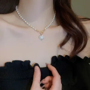 Close-up detail of a vintage style pearl necklace with a zircon heart pendant on a model