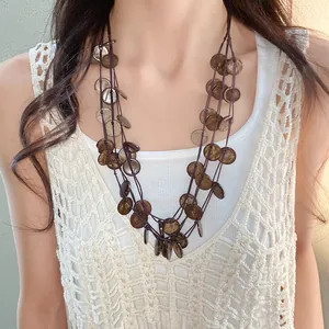 Detail of an irregular round coconut shell tassel necklace worn by a model in a boho style