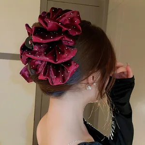 Elegant burgundy ruffled hair clip with sparkling rhinestones shown on model's hair