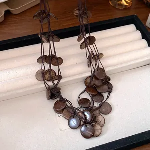 Detailed view of handmade ethnic style coconut shell tassel necklace on jewelry tray