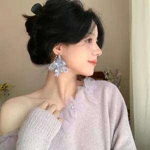 Detail view of stylish purple wool flower earrings with pearls on an Asian model