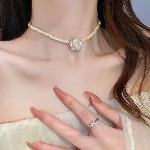 Close-up of elegant pearl necklace with camellia pendant and matching zircon ring