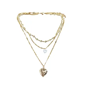 Elegante dreilagige Goldkette mit Herzmedaillon und Perlenanhänger auf weißem Grund