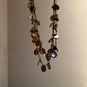 Detail of handmade boho necklace with irregular round coconut shell pieces on dark cords