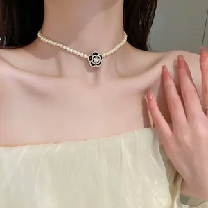 Elegant pearl choker necklace with black camellia flower pendant on Asian model.