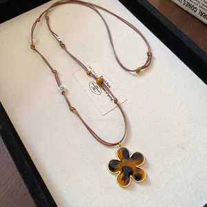 Detail view of a vintage leopard print flower pendant necklace with brown cord