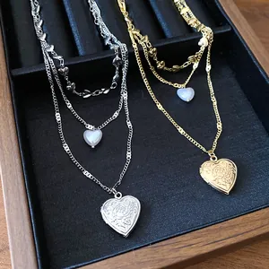 Nahaufnahme von eleganten dreilagigen Halsketten in Silber und Gold mit Herzanhängern.