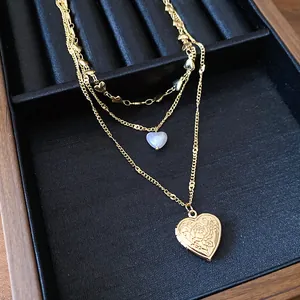 Detailaufnahme einer dreilagigen Goldhalskette mit Herzanhängern und Blumengravur.
