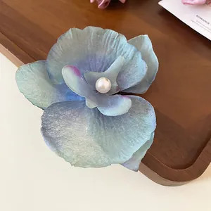 Detailed macro view of a blue and purple orchid fabric hair clip with a pearl center.