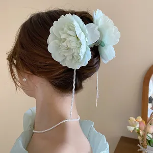 Detailed view of elegant mint green orchid hair clip with sparkling crystal tassels