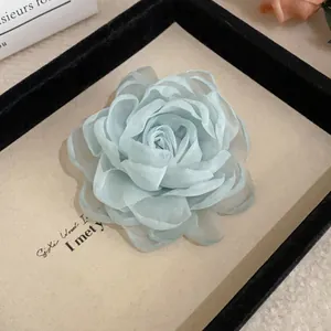 Close-up of a mint green fabric flower hair clip featuring delicate organza petals