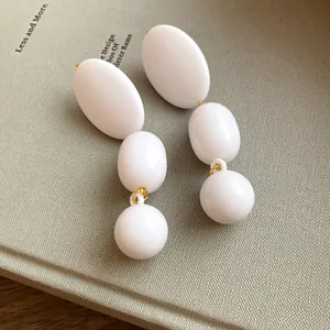 Orecchini pendenti retrò in acrilico bianco con perni in argento su libro strutturato.