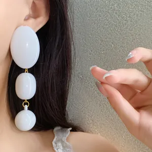 Dettaglio macro di orecchini a goccia ovali in acrilico bianco a tre livelli chic
