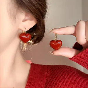 Close-up of red oil-dripped heart earrings featuring glossy texture and retro gold accents
