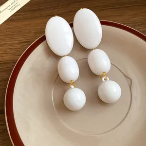Primo piano dettagliato di orecchini a pendolo ovali in acrilico bianco vintage