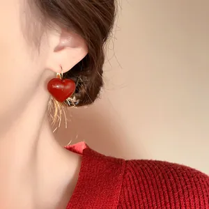 Detailed close-up of a vintage Ancora red heart earring worn on a female ear lobe
