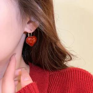 Detailed close-up showing an Ankola red heart-shaped hoop earring worn by a model