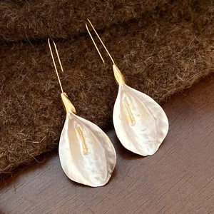 Dettaglio macro di orecchini vintage con petali bianchi e ganci finitura oro