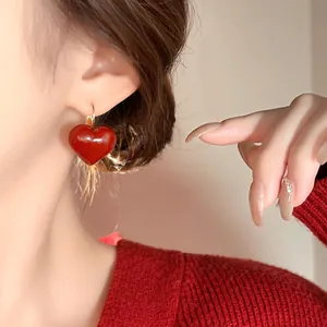 Close-up detail of a vintage Ancora red heart oil-drop earring worn by an Asian model