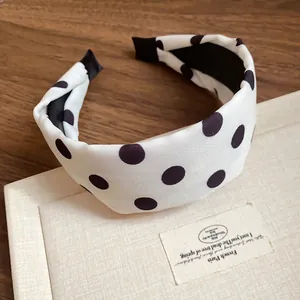 Detalle de una elegante diadema acolchada blanca con lunares negros clásicos