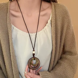 Detail view of a vintage faux wood geometric pendant necklace on a knitted cardigan