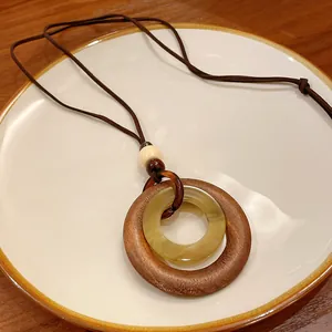Close-up detail of a vintage geometric wooden pendant necklace on a white ceramic plate.