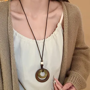 Close-up detail of vintage geometric double-ring pendant necklace with brown leather cord