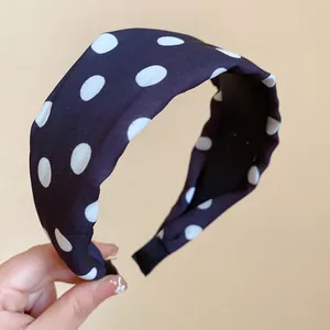 Primer plano de una diadema acolchada de tela azul marino con puntos blancos clásicos
