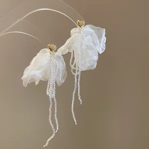 Vista dettagliata degli orecchini a fiore in rete bianca con cuori dorati e lunghe nappe