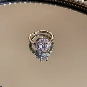 Close-up van een zilveren halo ring met ronde zirkoon op een spiegeloppervlak