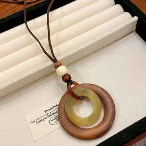 Close-up detail of retro wooden geometric pendant necklace with yellowish resin ring.
