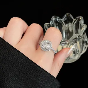 Detailopname van een zilverkleurige ronde halo-ring met zirkonia pavé aan een hand