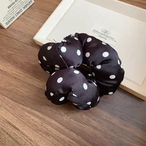Detalle de coletero abullonado de lunares blancos y negros sobre fondo de madera