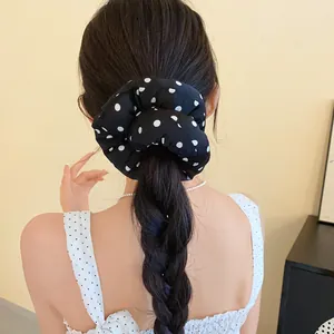 Detalle de coletero negro con lunares blancos en una coleta trenzada