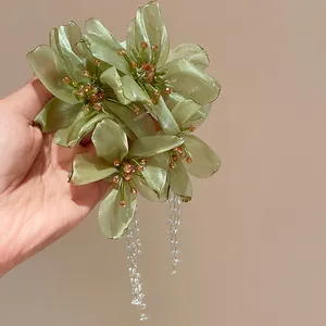 Detail shot of elegant green mesh flower earrings with long crystal tassels and silver needle.
