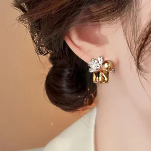 Exquisite close-up detail of square amber crystal and golden pearl stud earrings on ear