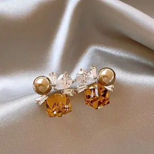 Close-up of elegant amber crystal earrings with pearls and pear-shaped zirconia