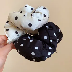 Detalle de coleteros de flores con lunares blancos y negros para el pelo en la mano