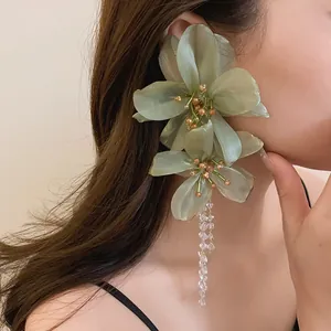 Detailed view of oversized green mesh flower earring with crystal tassel